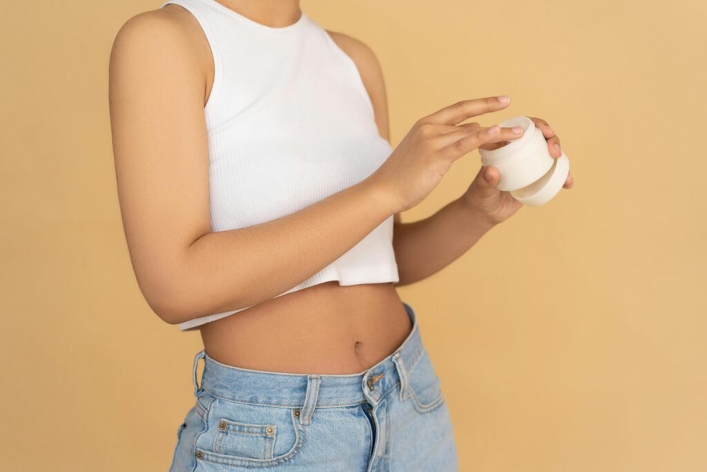 Close-up of a woman applying moisturizing cream in a studio setting with warm tones.